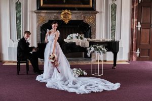 Svatba v klášteře v Tereziánském sále Břevnovského kláštera, snoubenci u klavíru po civilním obřadu